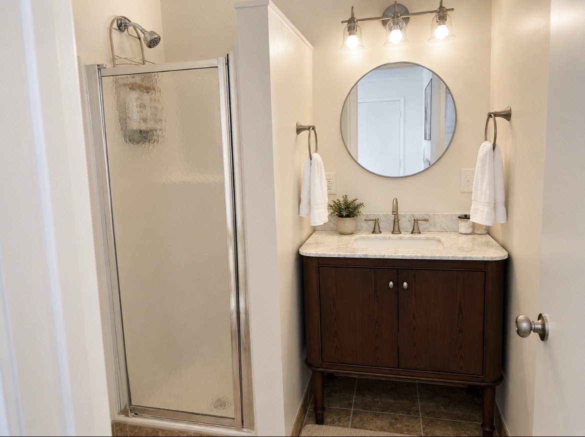 Bathroom with glass shower and round vanity mirror