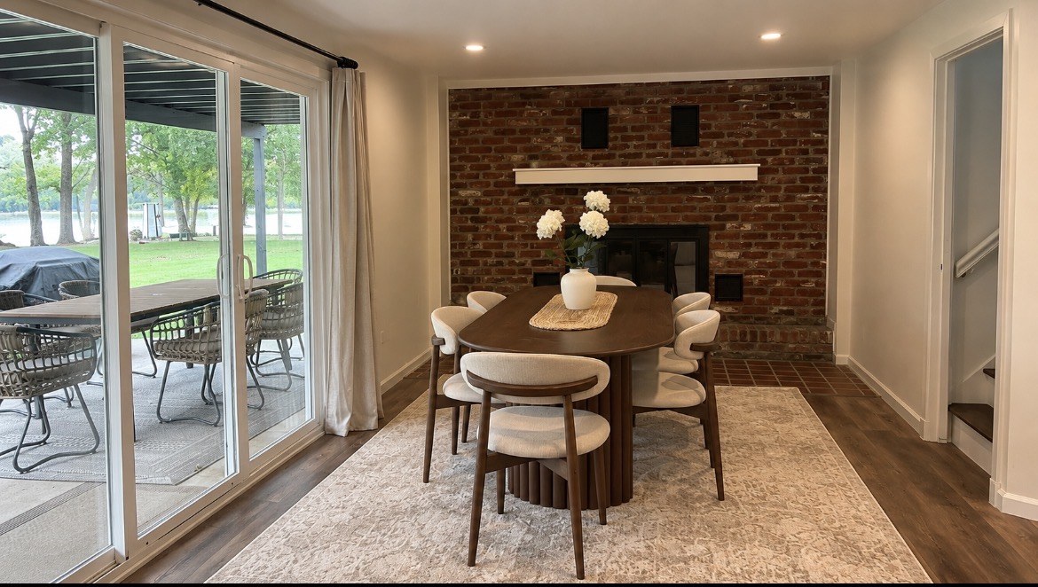 Downstairs dining table beside a brick fireplace and covered patio