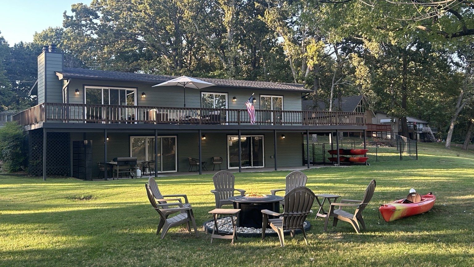 Lake-facing house, fire pit and red kayaks stored beneath the deck